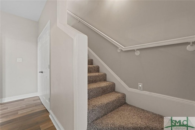 staircase featuring baseboards and wood finished floors