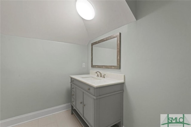 bathroom with vanity, baseboards, and lofted ceiling