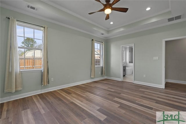 unfurnished bedroom with visible vents, a tray ceiling, crown molding, and wood finished floors