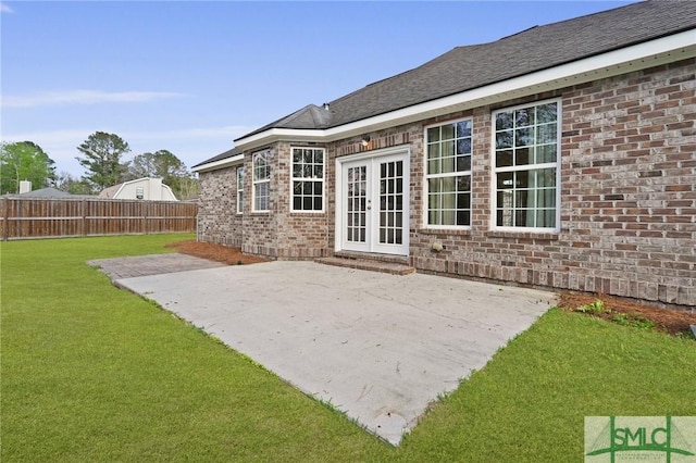 rear view of property featuring a lawn, a patio area, fence, brick siding, and french doors