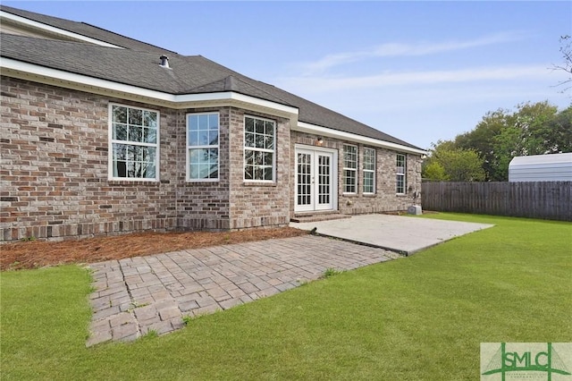 rear view of property featuring a patio, french doors, brick siding, a yard, and fence