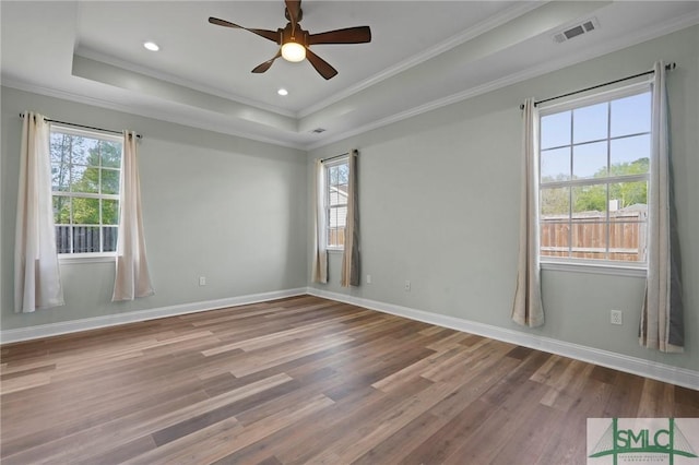 unfurnished room featuring a raised ceiling, crown molding, visible vents, ceiling fan, and wood finished floors
