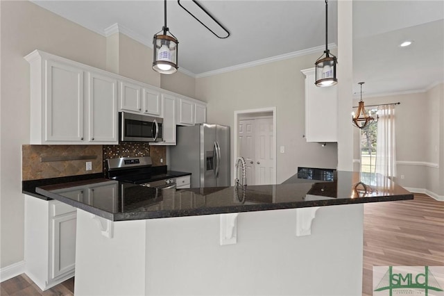 kitchen with a kitchen bar, tasteful backsplash, white cabinetry, appliances with stainless steel finishes, and wood finished floors