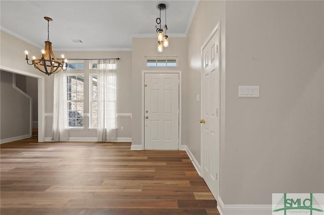 foyer entrance with a notable chandelier, baseboards, crown molding, and wood finished floors