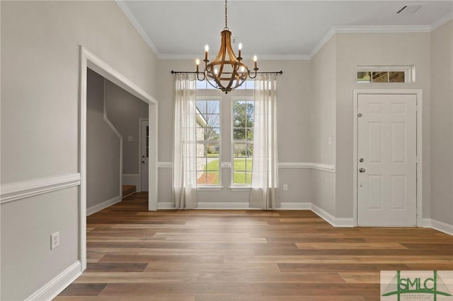 unfurnished dining area featuring ornamental molding, baseboards, a chandelier, and wood finished floors