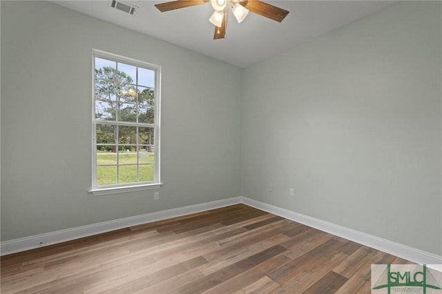 empty room featuring visible vents, baseboards, a ceiling fan, and wood finished floors