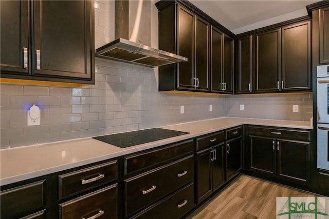 135 Sessile Oak Dr, Savannah, GA 31419 - kitchen with light countertops, wall chimney exhaust hood, black electric stovetop, light wood-style flooring, and decorative backsplash