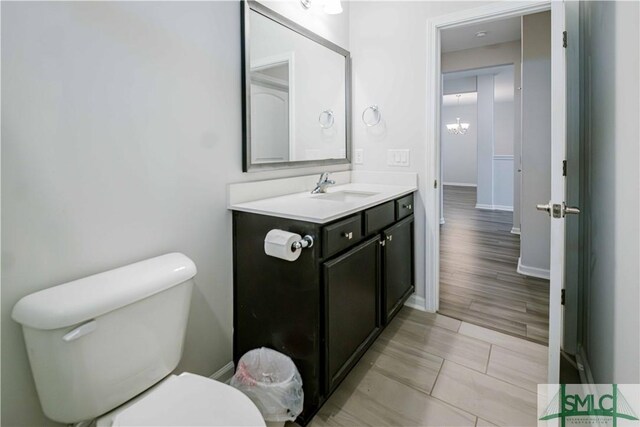 135 Sessile Oak Dr, Savannah, GA 31419 - half bathroom with baseboards, toilet, wood finished floors, vanity, and a notable chandelier
