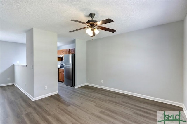 unfurnished living room with baseboards, dark wood-style floors, ceiling fan, and a textured ceiling
