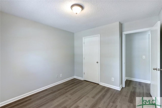unfurnished bedroom with baseboards, dark wood-style flooring, and a textured ceiling