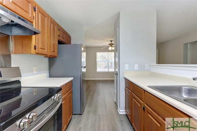 kitchen featuring light countertops, ceiling fan, stainless steel appliances, under cabinet range hood, and a sink