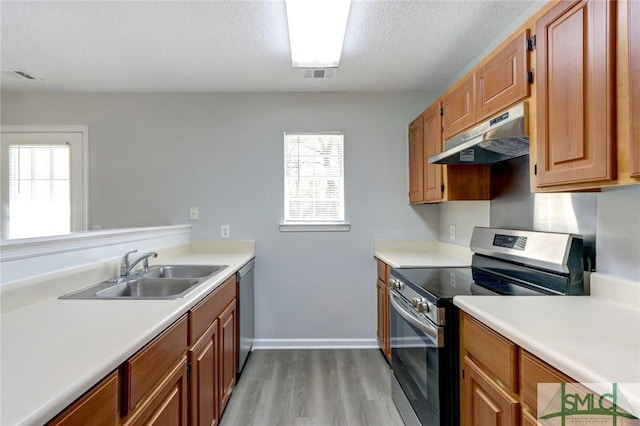kitchen featuring light countertops, a sink, appliances with stainless steel finishes, under cabinet range hood, and visible vents
