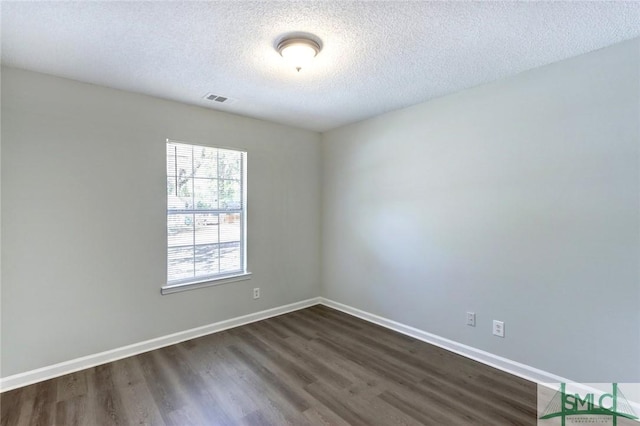 empty room with visible vents, a textured ceiling, baseboards, and dark wood finished floors