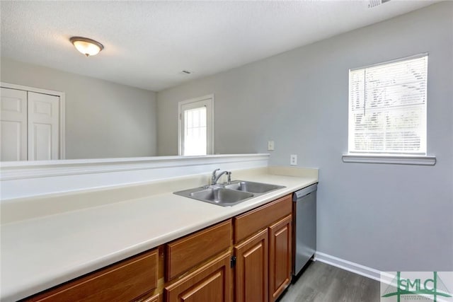 kitchen with dark wood-style flooring, light countertops, brown cabinets, a sink, and stainless steel dishwasher