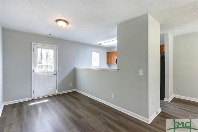 foyer with dark wood finished floors, baseboards, visible vents, and a textured ceiling