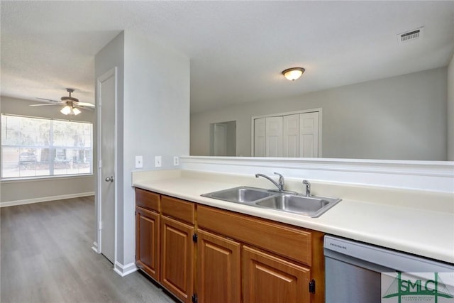 kitchen featuring light countertops, a sink, visible vents, dishwasher, and brown cabinetry