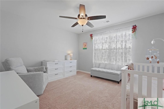 bedroom featuring light carpet, visible vents, a nursery area, and ceiling fan