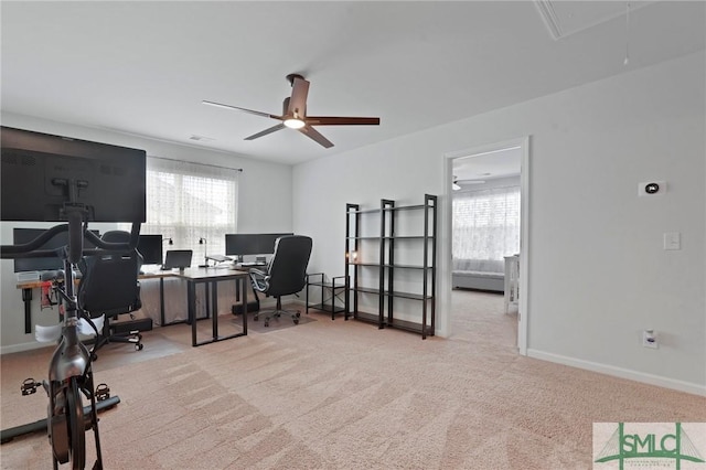 carpeted office space featuring attic access, baseboards, and ceiling fan