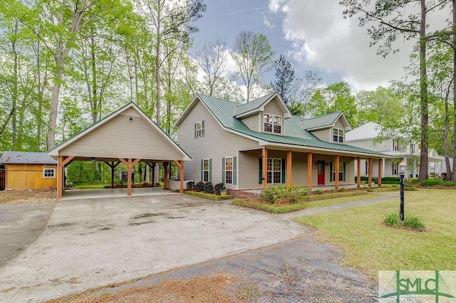 view of front of home featuring metal roof, concrete driveway, a front lawn, covered porch, and a detached carport