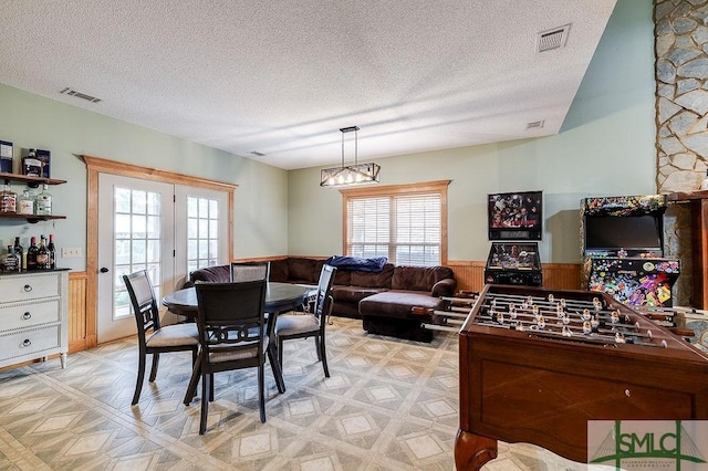 dining room featuring a wainscoted wall, light floors, a textured ceiling, and visible vents