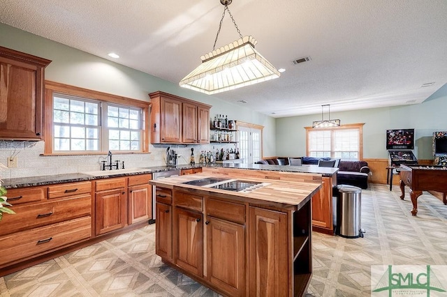 kitchen featuring a sink, open shelves, a center island, black electric cooktop, and visible vents