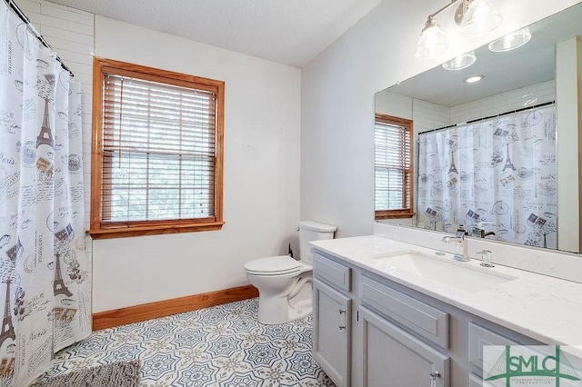 bathroom with vanity, toilet, baseboards, a textured ceiling, and tile patterned floors