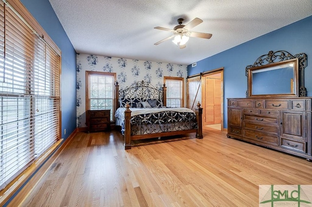 bedroom featuring a textured ceiling, light wood-style flooring, and wallpapered walls