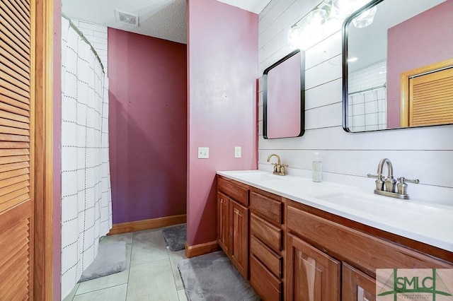 bathroom with a sink, double vanity, visible vents, and tile patterned floors