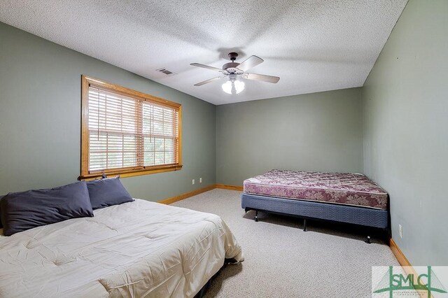carpeted bedroom with a textured ceiling, baseboards, ceiling fan, and visible vents