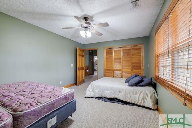 bedroom featuring a closet, a textured ceiling, visible vents, baseboards, and light carpet