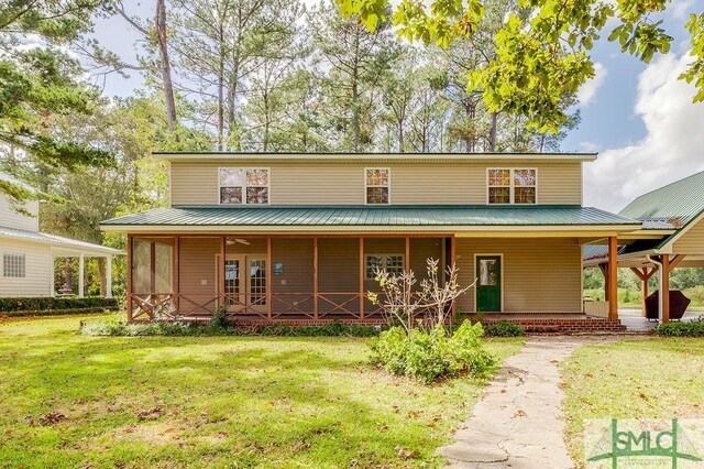 rear view of property with a lawn, covered porch, and metal roof