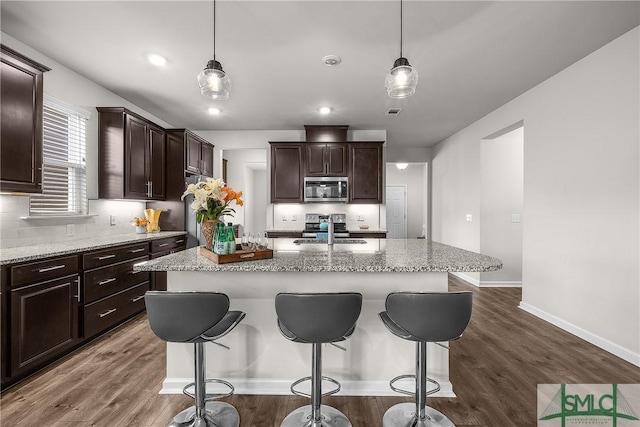 224 Benelli Dr, Pooler, GA 31322 - kitchen with stainless steel microwave, an island with sink, a kitchen bar, and a sink