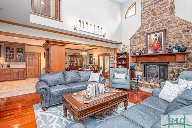57 Delegal Rd, Savannah, GA 31411 - living area with light wood-style floors, crown molding, a stone fireplace, a high ceiling, and a notable chandelier
