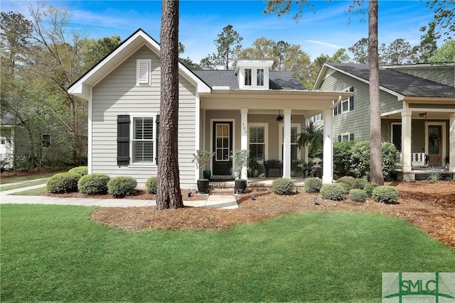 view of front facade with a front yard, ceiling fan, and covered porch