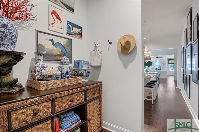 corridor featuring a notable chandelier, dark wood-style floors, and baseboards