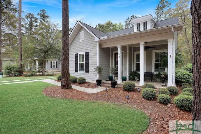 view of front of house with roof with shingles, covered porch, a front yard, and a ceiling fan