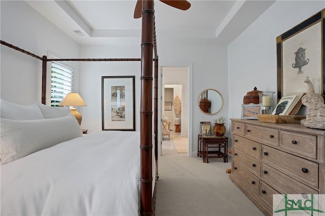 carpeted bedroom featuring visible vents, a tray ceiling, a ceiling fan, and ensuite bathroom