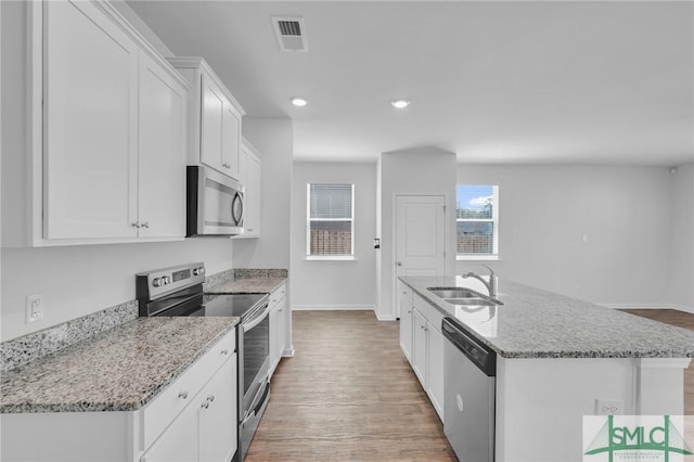 kitchen with visible vents, white cabinets, a sink, appliances with stainless steel finishes, and light wood-style floors