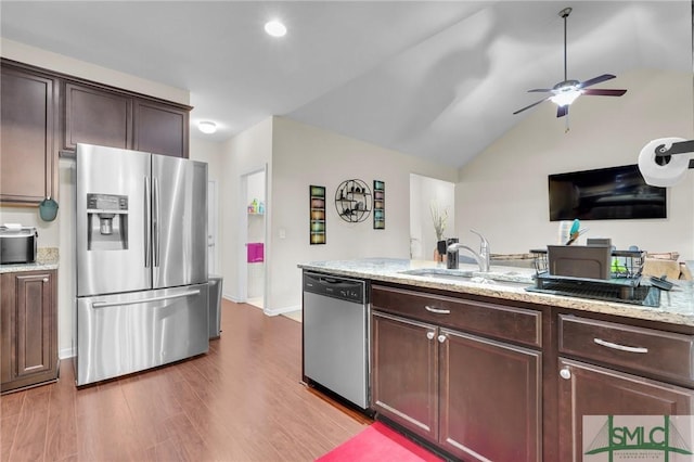 kitchen with light wood-style floors, ceiling fan, appliances with stainless steel finishes, light stone counters, and a sink