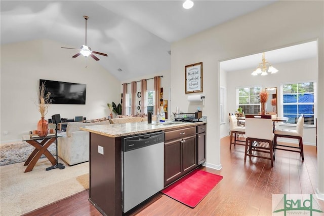 kitchen featuring ceiling fan with notable chandelier, stainless steel dishwasher, wood finished floors, a sink, and lofted ceiling