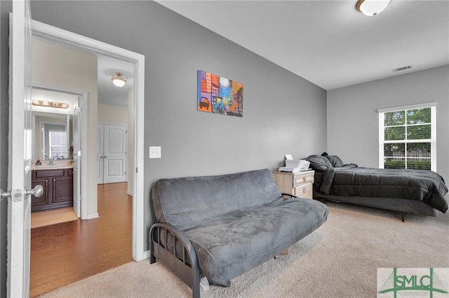 bedroom featuring baseboards, carpet floors, visible vents, a sink, and wood finished floors