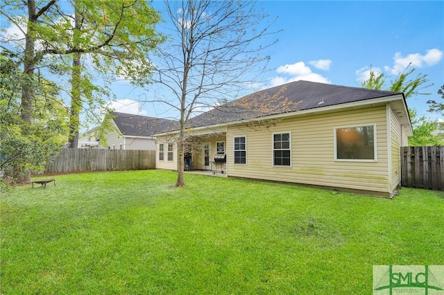 rear view of property featuring a fenced backyard and a lawn