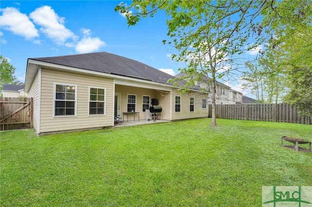 rear view of property featuring a patio, a yard, and a fenced backyard