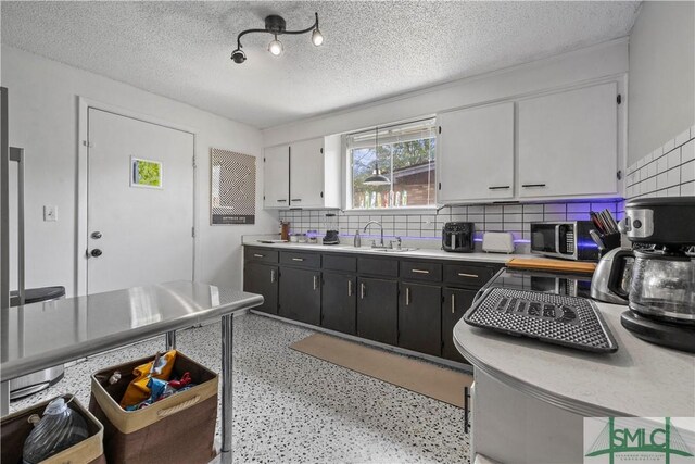 109 Seminole St, Savannah, GA 31406 - kitchen with white cabinets, stainless steel microwave, a sink, light countertops, and dark cabinetry