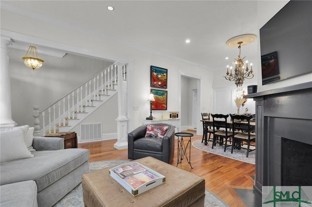 living area with a chandelier, crown molding, a fireplace with flush hearth, stairway, and recessed lighting