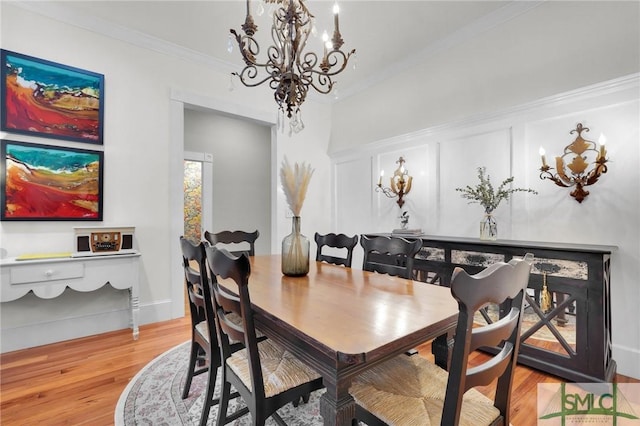 dining area with a chandelier, light wood-style flooring, and crown molding