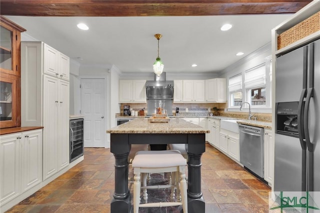 kitchen featuring stainless steel appliances, beverage cooler, a sink, crown molding, and stone tile flooring