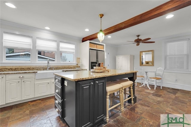 kitchen with stainless steel fridge, a sink, stone tile flooring, a kitchen breakfast bar, and beamed ceiling
