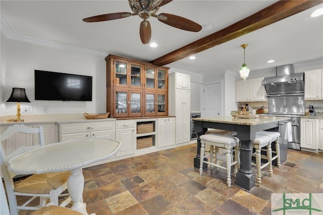 kitchen featuring wall chimney range hood, recessed lighting, stone tile floors, ceiling fan, and backsplash