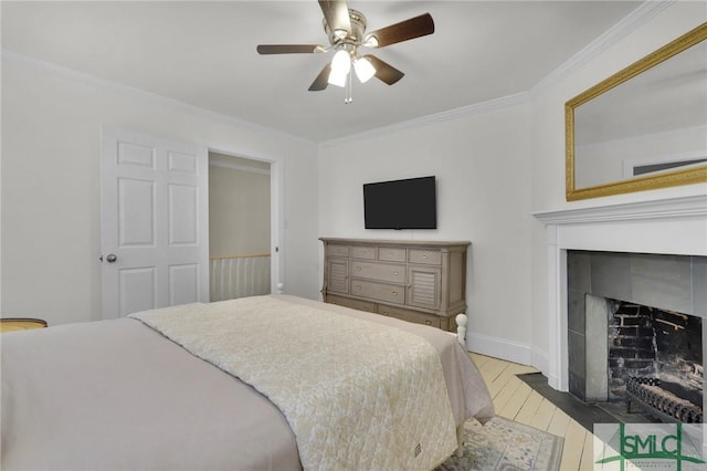 bedroom with ornamental molding, wood finished floors, a fireplace with flush hearth, baseboards, and ceiling fan